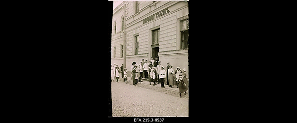 Sõjapäevil organiseeritud nn Tatjana komitee (Vene tsaari Nikolai II
                    tütre suurvürstinna Tatjana patronaaži all tegutsenud sõja läbi kannatanutele
                    ajutise abi andmise organisatsioon) märkide müümine Posti tänaval Rahukohtu
                    hoone ees.