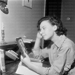 Barbara Zacconi, seduta ad uno scrittoio all'interno di una villa,  tiene in mano la foto di Ermete Zacconi - piano medio