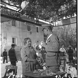 L'attore Roberto Risso, vestito da carabiniere, e una donna - un'attrice, la Merlini (?) - colti in un momento di pausa sul set del film "Pane, amore e gelosia" (?). Piano americano