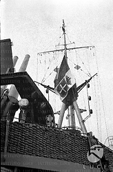 La bandiera italiana sull'albero di una nave da guerra, un cannone puntato verso l'alto