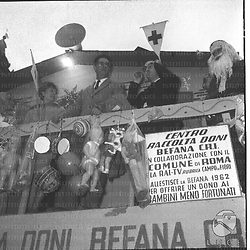 Chiusano, Navona e Mannucci sul  palco, dove vengono raccolti i doni per i bambini, con la 'Befana' e 'Babbo Natale' - totale