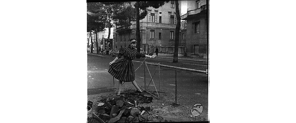 Una modella con un vestito a strisce in posa in una strada di Roma dove sono in corso dei lavori. Campo lungo