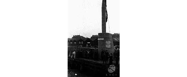 Marinai e ufficiali della Marina Militare Italiana e della Marina Militare Tedesca sul molo durante la celebrazione militare, si vede il monumento in onore del Sommergibile Barbarigo