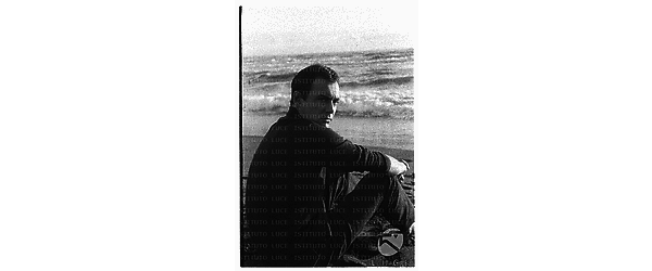Maurice Ronet seduto sulla battigia della spiaggia di Ostia - piano americano