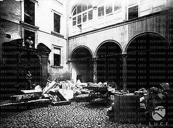 'Roma sparita' [Riproduzione di fotografia del secondo Ottocento con veduta parziale di cortile rinascimentale di palazzo romano occupato da pezzi di marmo, accumulati in un angolo, e da un carretto] - Totale
