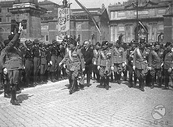 Roma Mussolini, accompagnato da autorità e gerarchi, fra cui il ministro Paribeni, Starace e Ricci, passa in rassegna uno schieramento di giovani camicie nere in piazza del Popolo durante la IV Leva Fascista