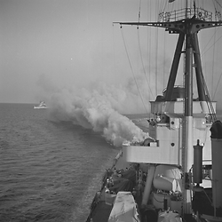 Una nave da guerra italiana lancia una cortina fumogena dal ponte di poppa