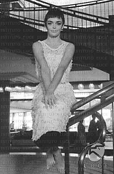 Barbara Steele in abito da sera e a piedi nudi, seduta su una balaustra all'interno dell'Hotel Hilton; totale