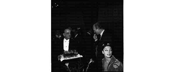 Un cameriere porge da bere ad Armando Trovajoli, sulla destra della foto seduta Anna Maria Pierangeli - piano americano