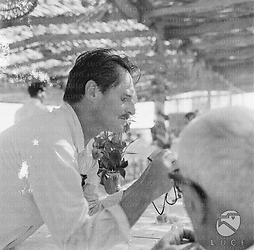 Pietro Germi  di profilo appioggiato con i gomiti al tavolo del ristorante all'aperto