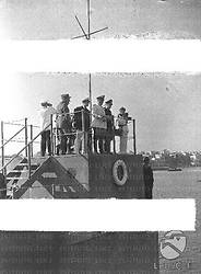 Nettunia Mussolini ed altre autorità sono in piedi in una torretta sul molo di Anzio per assistere ad una esercitazione dei servizi antincendi
