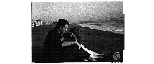 Gli attori Maurice Ronet e Marie Versini seduti sulla battigia della spiaggia di Ostia - campo lungo