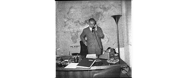 Felice Ippolito ripreso in ufficio in piedi dietro la scrivania al telefono - piano americano
