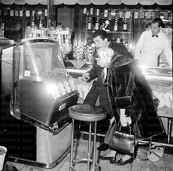 Lorella De Luca (in pelliccia) e Toni Dallara scelgono un disco al jukebox davanri al bancone di un bar