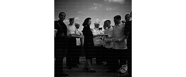 Una rappresentante dei fasci femminili accompagnata da un esponente del P.N.F. consegna una lettera ad un marinaio alla presenza di altri militari