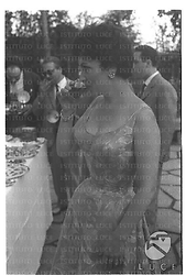 Gina Lollobrigida beve un drink al tavolo del buffet durante un ricevimento nella sua villa per la ripresa della sua attività cinematografica - piano americano