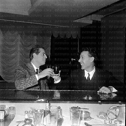 Franco Ferrara e Arturo Basile conversano al bancone del bar probabilmente di un teatro