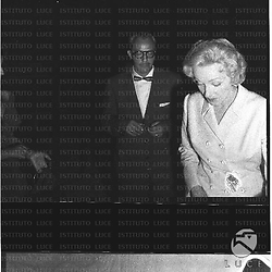 Marlene Dietrich guarda verso il basso, osservata da un uomo con gli occhiali; piano medio