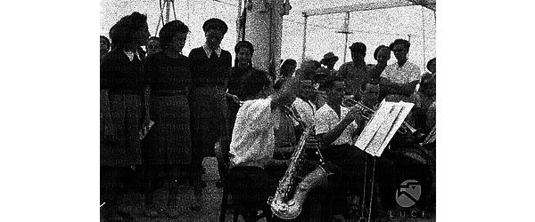 Musicisti e cantanti di un coro femminile durante una prova del concerto sul ponte della nave proveniente dall'A.O.I.