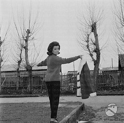 Annette Funicello posa tenendosi in equilibrio sulla recinzione in pietra di un giardino