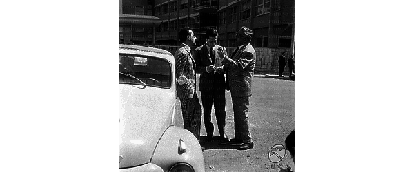 Roma Arnoldo Foà, appoggiato a un'automobile posteggiata, discute con Mario Carotenuto e Marcello Mastroianni