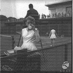 La tennista Lea Pericoli mentre beve un bicchiere d'acqua ai margini del campo da tennis. Piano americano