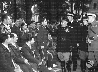 Bologna Nel giardino del centro orotpedico "Putti" , Benito Mussolini saluta, posandogli la mano sulla spalla, un giovane soldato con il bastone
