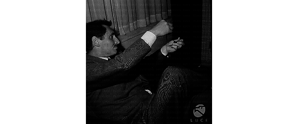 Pietro Germi, seduto su una poltrona, esamina la pellicola