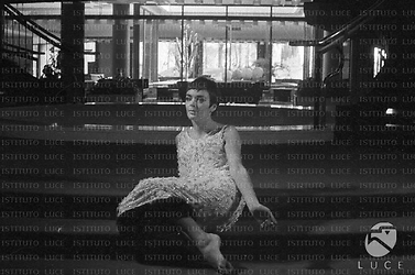 Barbara Steele in abito da sera e a piedi nudi, seduta su alcuni gradini all'interno dell'Hotel Hilton; totale
