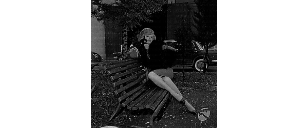 Margaret Lee seduta su una panchina in un giardinetto di periferia - totale