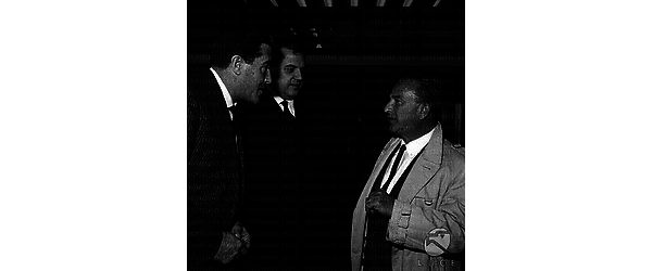 Il regista George Sherman discute con due uomini. Piano medio