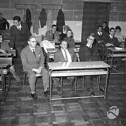 Roma Il regista Sherman, il Direttore Fioravanti ed un uomo seduti ad un banco all'interno di una classe