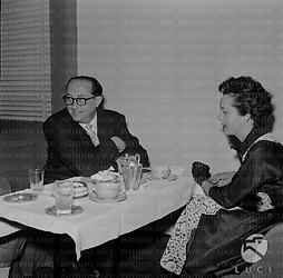 Henry Koster seduto al tavolo di un locale accanto ad una donna - piano americano