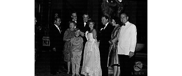 Venezia Silvia Syms in abito da sera insieme ad un gruppo di persone; alla sua destra un bambino, dietro Basil Dearden
