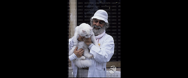 Armando Acosta (Baba Ganapati) con in braccio un gatto bianco