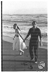 Gli attori Maurice Ronet e Marie Versini in piedi per mano sulla battigia della spiaggia di Ostia - campo medio