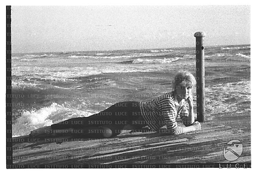 L'attrice Ann Smyrner su una spiaggia di Ostia, distesa su una passerella di legno - totale