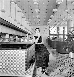 Barbara Steele, con un calice in mano e in abito da sera, nel bar-self service dell'Hotel Hilton. Evidente la prospettiva del salone; campo medio