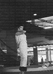 Barbara Steele in abito da sera, sotto una scalinata circolare all'interno dell'Hotel Hilton; totale