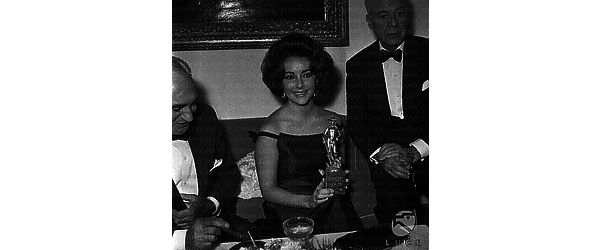 Roma Elizabeth Taylor al cocktail in occasione del David di Donatello, tiene in mano la statuetta, accanto c'è il produttore Walter Wagner