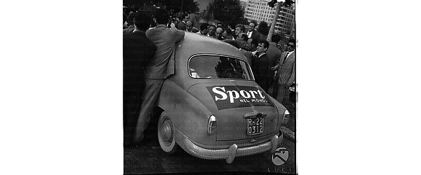 Una macchina con lo sponsor della rivista "Sport nel mondo", intorno diverse persone - piano americano