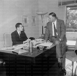 Umberto Orlandi e Tony Randall discutono stando seduti ad una scrivania. Totale