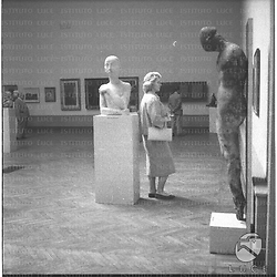 Una donna in visita alla Galleria di arte moderna ripresa avanti a sculture e quadri - campo medio