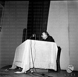 Diego Fabbri tiene la sua conferenza seduto ad un tavolino con una lunga tovaglia bianca su un palco