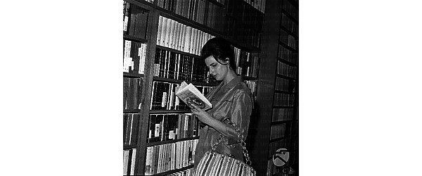 Mentre legge  il l libro sulla vita di Eleonora Duse davanti agli scaffali di una libreria Piano medio