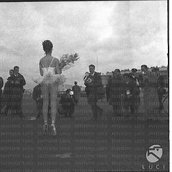 Vera Tschechowa ripresa in aereoporto con fiori in mano sotto i flash dei fotografi - campo medio