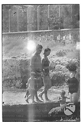Un uomo, una ragazza ed un bambino ripresi in costume sul molo di Santa Marinella, accanto altri villeggianti - totale