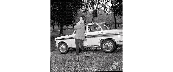 Pina Bottin in posa davanti ad un'automobile Fiat 1100; esterno; campo medio