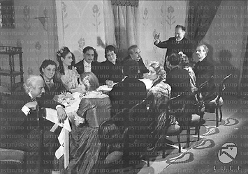 Roma Zoe Incrocci (terza da sinistra) e altri attori della compagnia seduti intorno ad una tavola imbandita