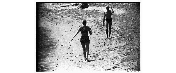 Ingrid Bergman (di spalle) uscendo dall'acqua a Santa Marinella fa un cenno di saluto ad un uomo in costume che si dirige verso di lei - campo lungo
